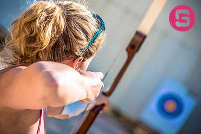 Woman with bow and arrow aiming at a target